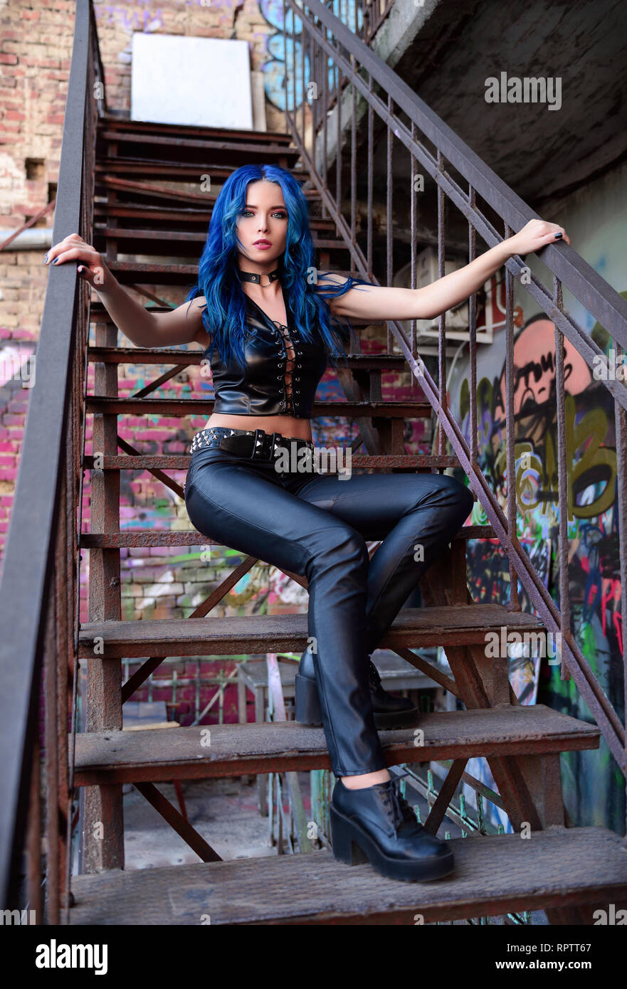 Roca hermosa chica con el pelo azul (modelo informal), vestido con los  pantalones de cuero negro y el tema, se sienta en la escalera Fotografía de  stock - Alamy