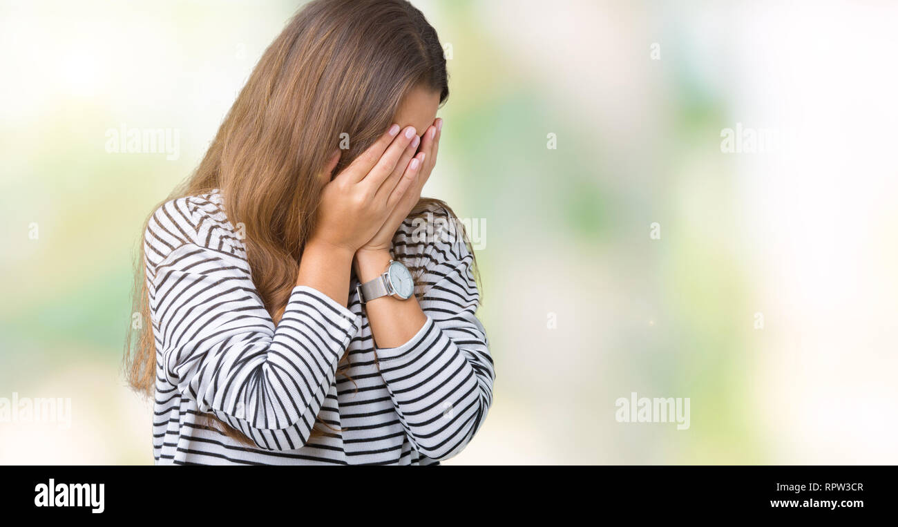 Morena hermosa joven mujer vistiendo un suéter de rayas sobre antecedentes  aislados con expresión triste que cubren la cara con las manos mientras  llora. Depresión Fotografía de stock - Alamy