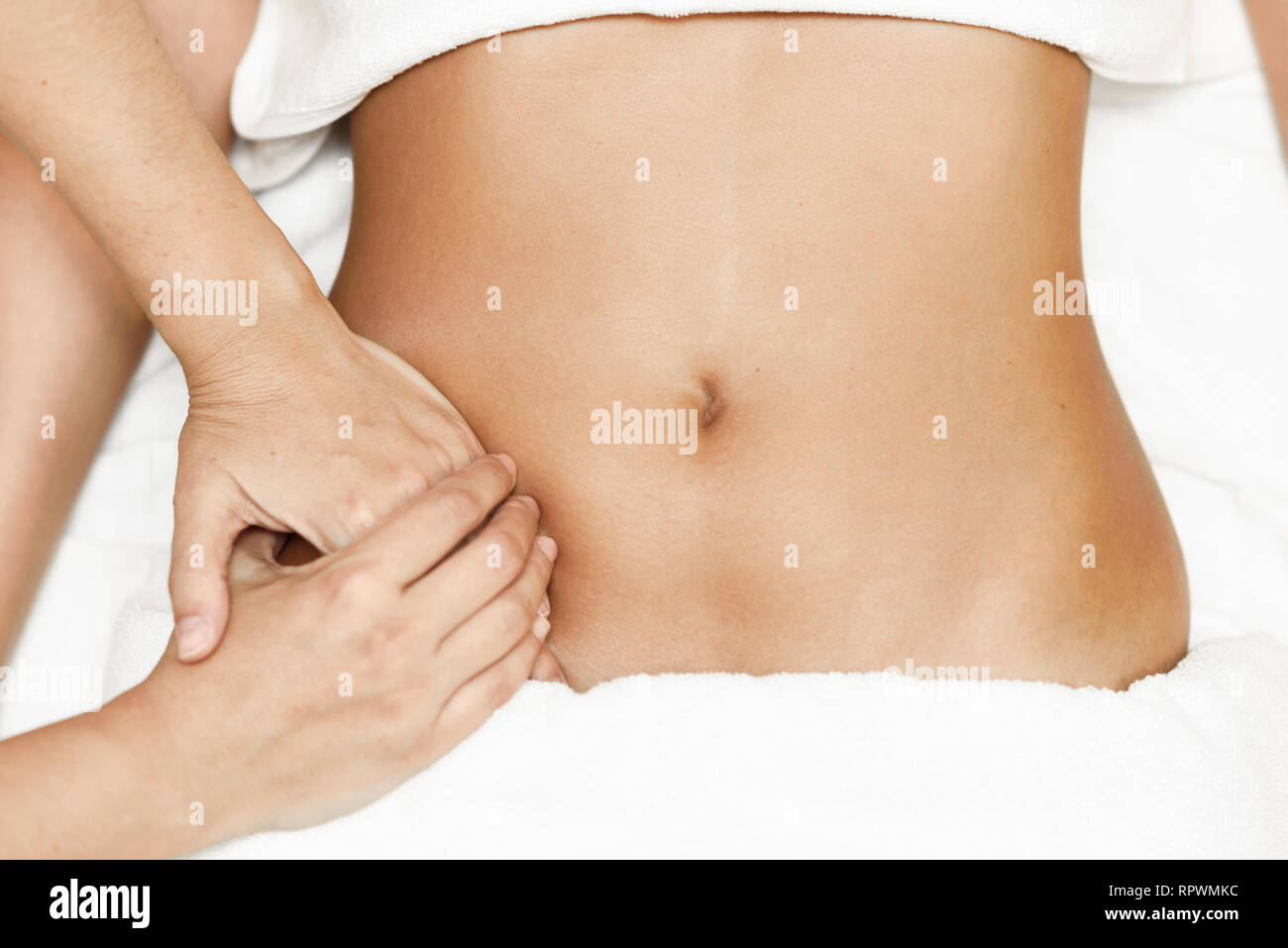 Manos abdomen femenino.terapeuta de masaje aplicando presión sobre el vientre. Foto de stock