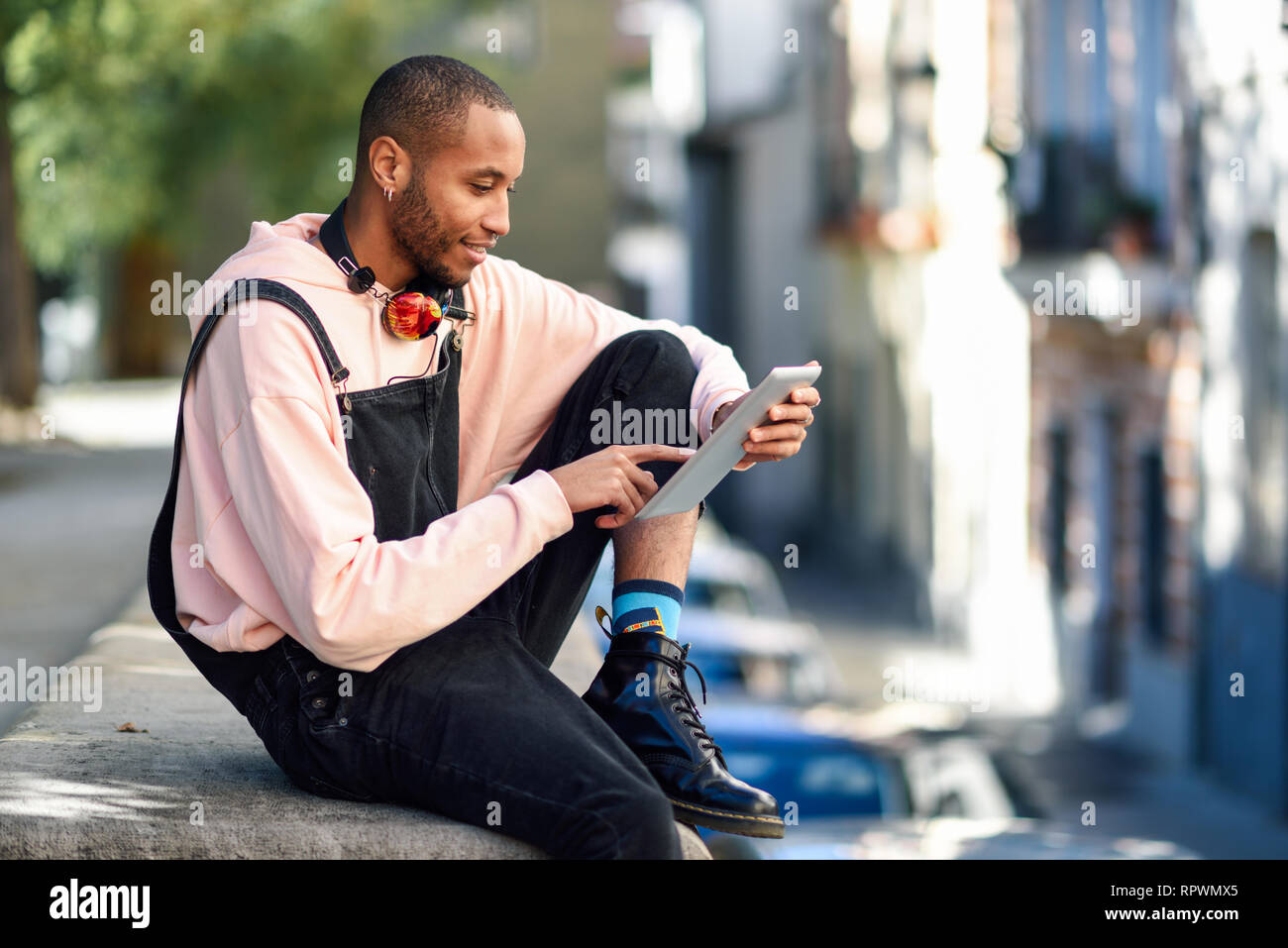 Joven negro mediante tableta digital en el contexto urbano. Foto de stock