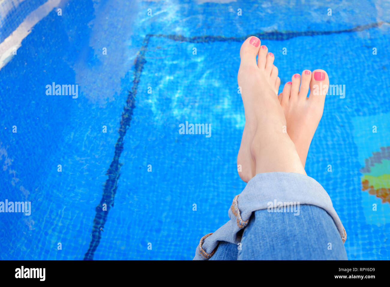 Cruzó mujer pies en blue jeans por piscina Fotografía de stock - Alamy