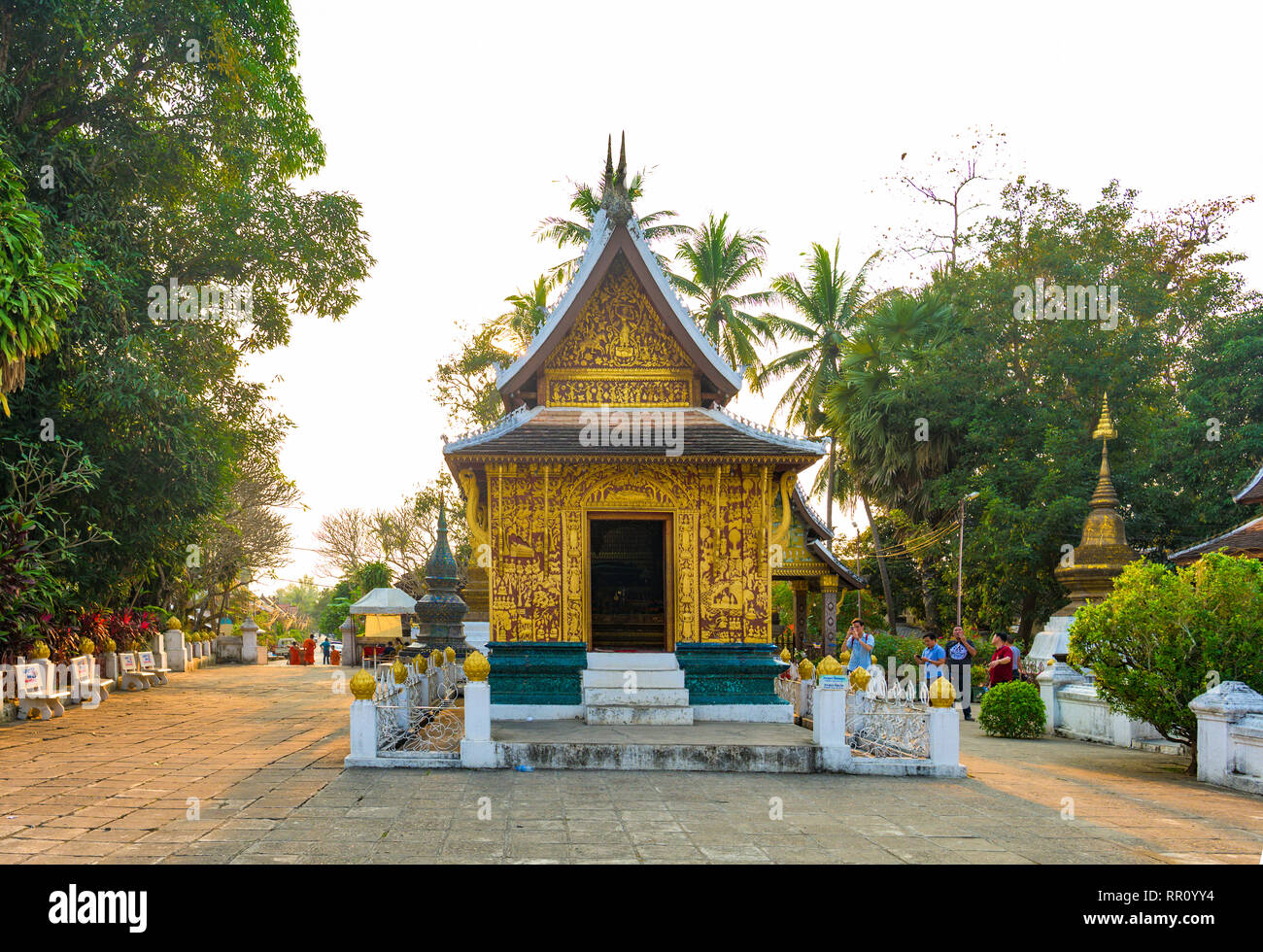 LUANG PRABANG - LAOS - 11 de febrero de 2019 algunos turistas son caminar y tomar fotos en el hermoso Wat Xieng Thong (Templo) de Oro de la ciudad al atardecer en Foto de stock