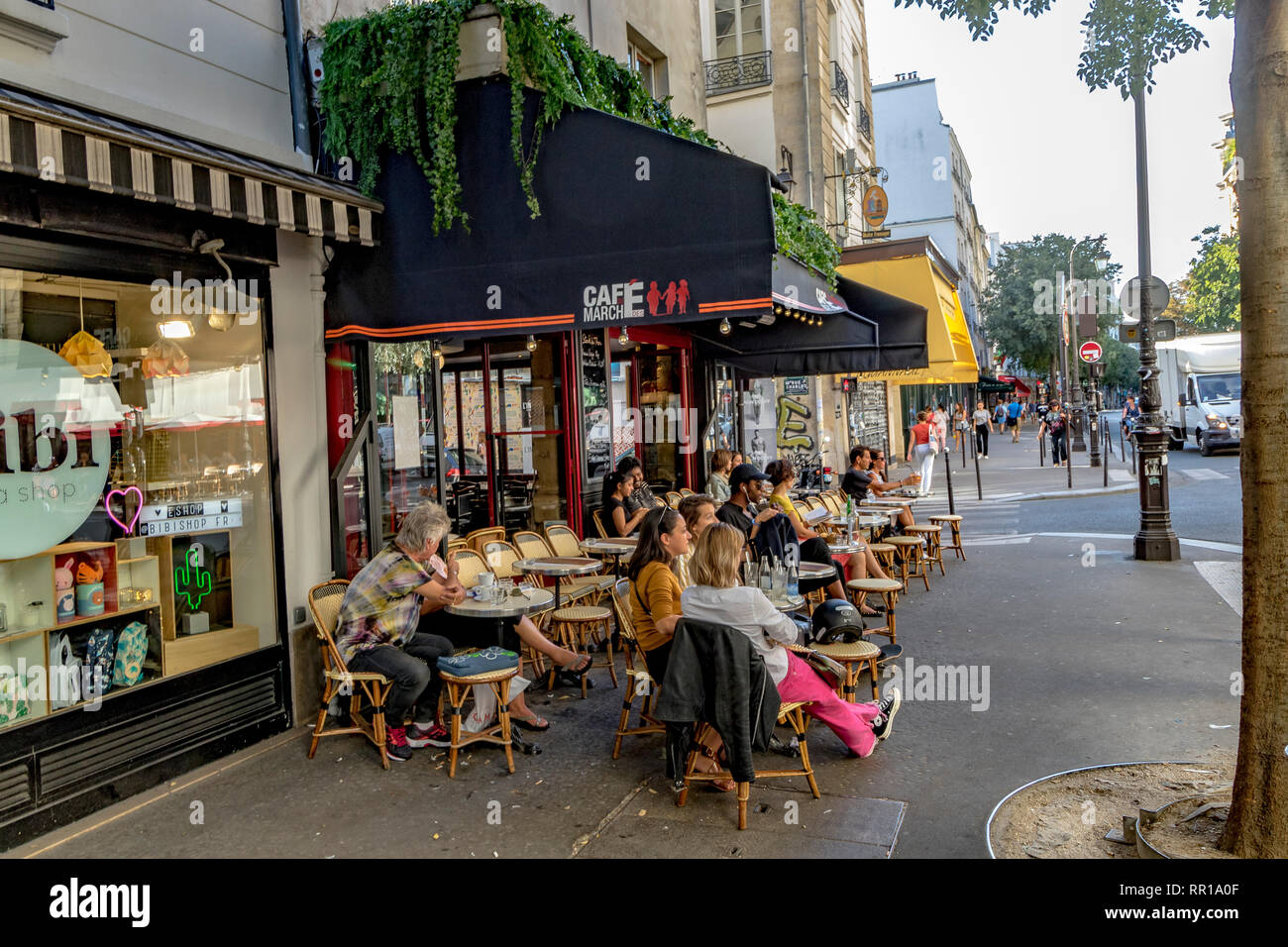 Gente sentada afuera en el pavimento en el Cafe du Marche des Enfants Rouges, en la Rue de Bretagne, París, Francia Foto de stock