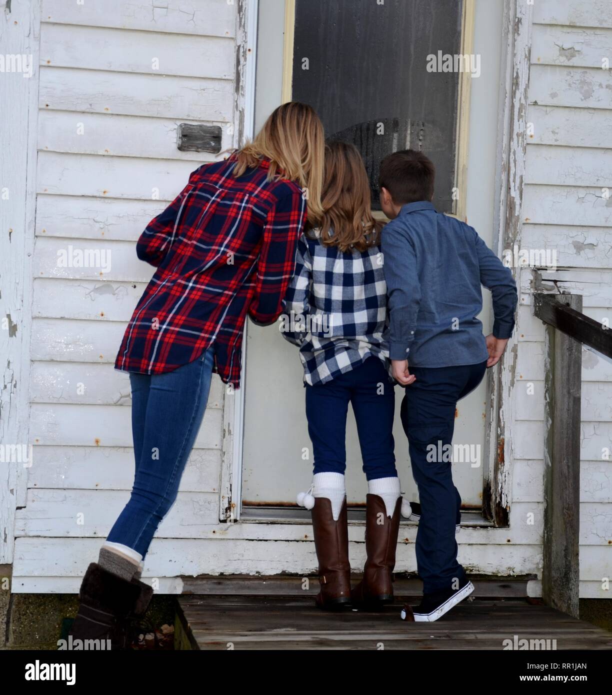 3 niños buscando en una casa abandonada Foto de stock