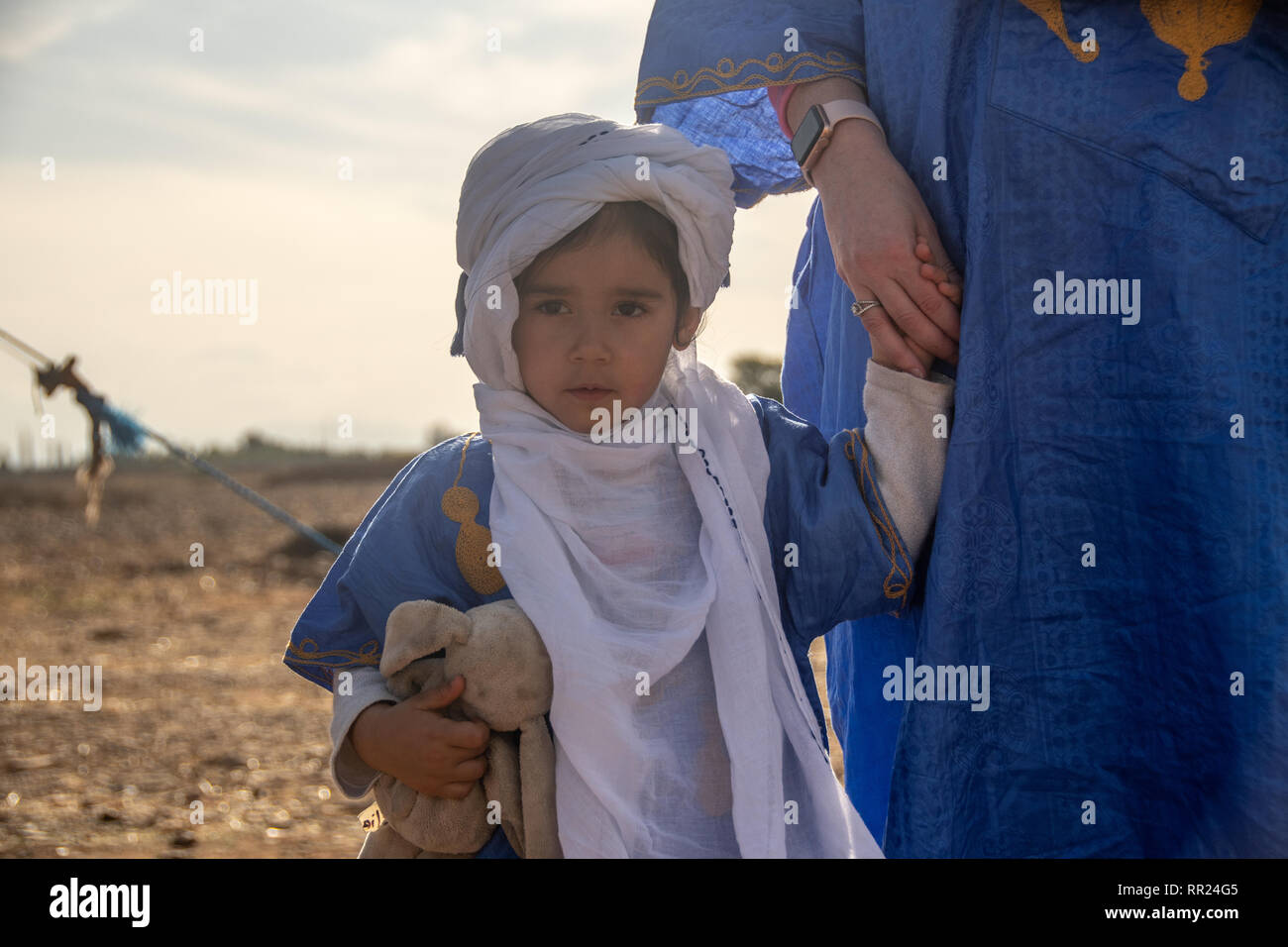 Niña en traje tradicional árabe sosteniendo la mano de su madre. Foto de stock