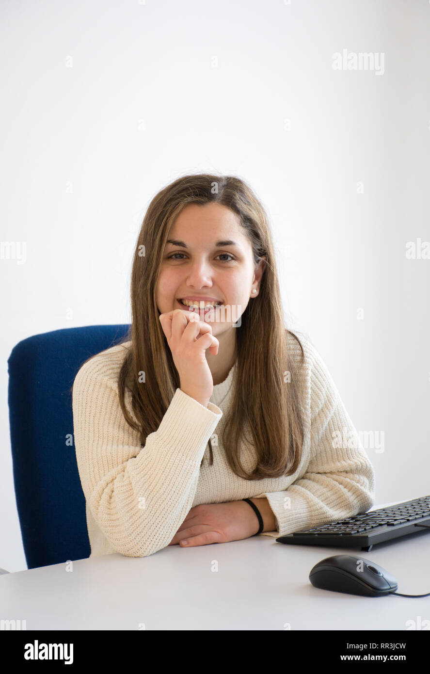 joven secretario sonriente en el trabajo en una oficina blanca frente a la computadora. Concepto de servicio al cliente agradable y alegre. Foto de stock