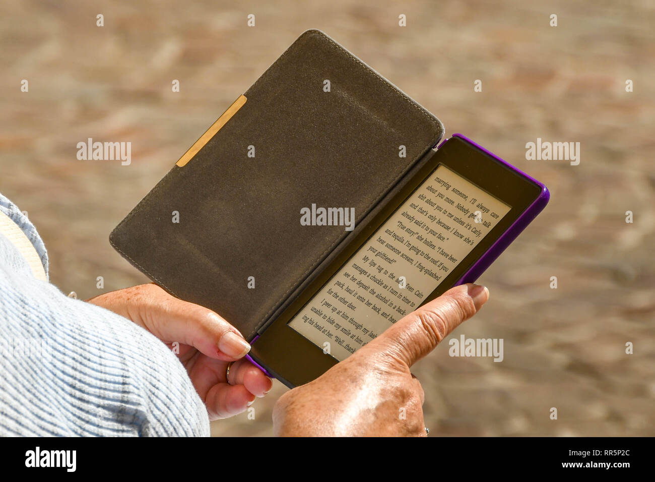 GARDONE RIVIERA, Italia - Septiembre 2018: Persona leyendo una novela sobre un dispositivo e-reader. Foto de stock