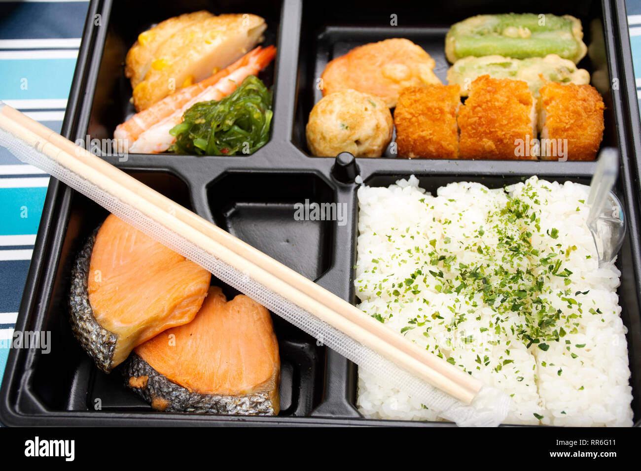 Caja bento comida japonesa arroz frito y el salmón y las verduras con otros en la mesa de la cocina en el jardín al aire libre en el pueblo de Japón en Caja bento comida japonesa arroz frito y el salmón y las verduras con otros en la mesa de la cocina en el jardín al aire libre en el pueblo de Japón en
