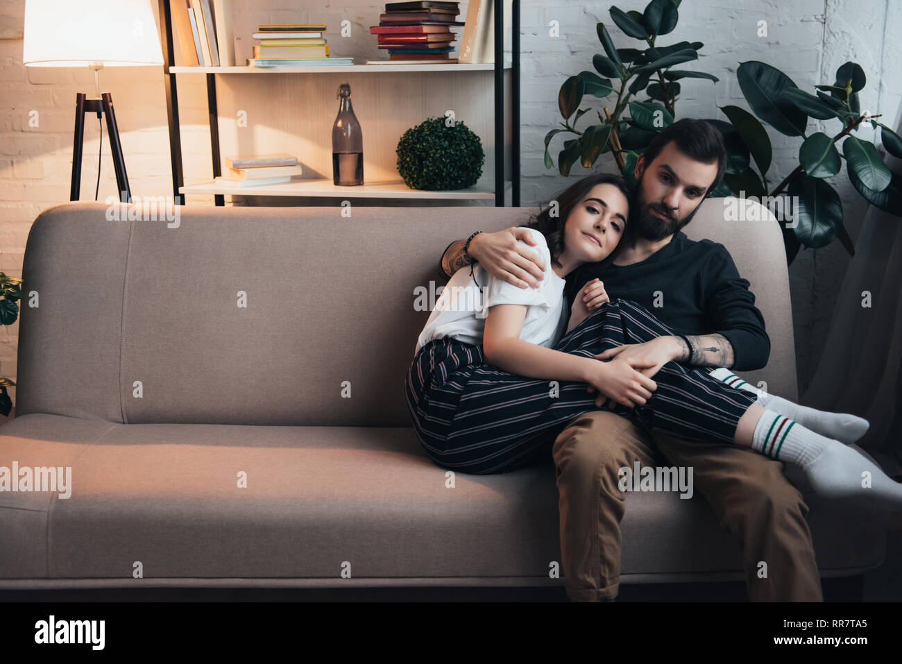Un hombre y una mujer abrazados en el sofá mientras ve la televisión  Fotografía de stock - Alamy