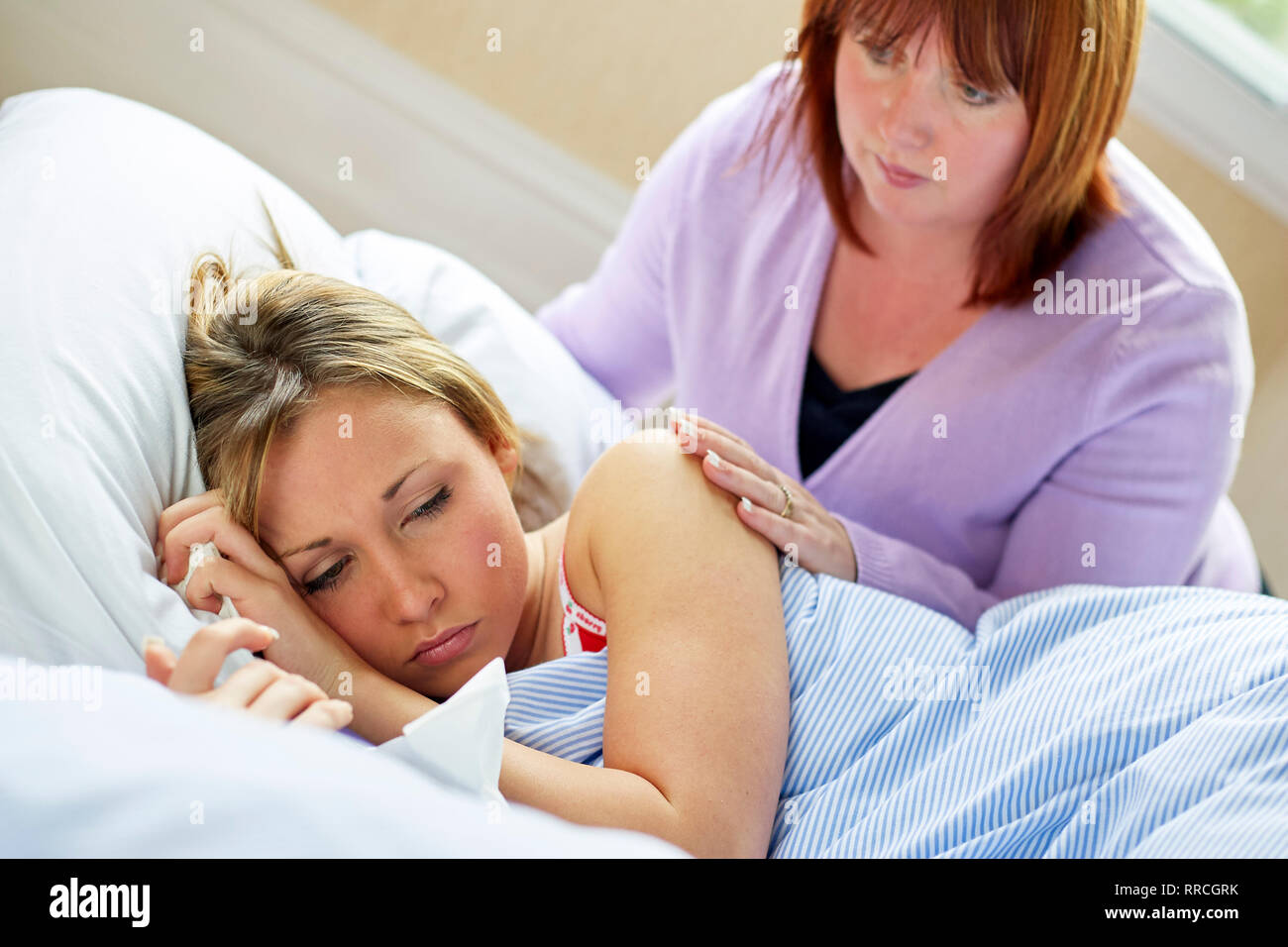 Adolescente sentado en la cama con la gripe Foto de stock