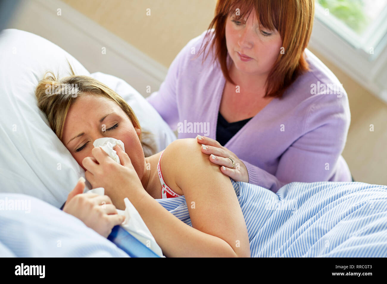 Adolescente sentado en la cama con la gripe Foto de stock