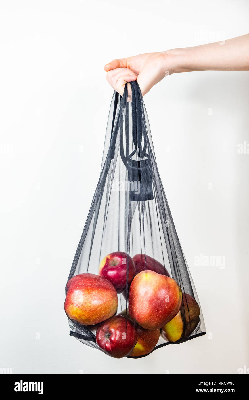 La celebración de una cadena reutilizable bolsa llena de manzanas. Concepto de embalaje ecológico sostenible: compras de comestibles con una bolsa de usos múltiples para reducir el pie ecológico Foto de stock