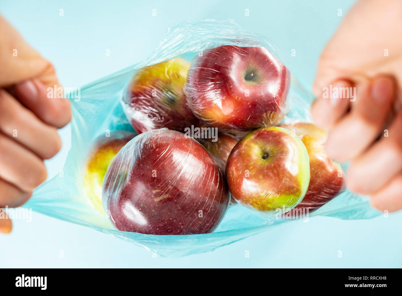 El uso de plástico excesivo concepto: manzanas frescas en la cocina envuelva en una bolsa de plástico. Injustificadamente sobre productos de alimentación envasados, vista desde arriba Foto de stock