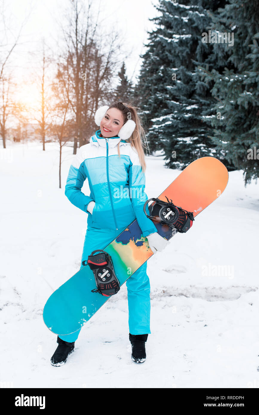 Hermosa chica un mono en un fondo de nieve, en manos de una junta de snowboard. Las emociones de la felicidad del placer de la mujer descanso, el resort