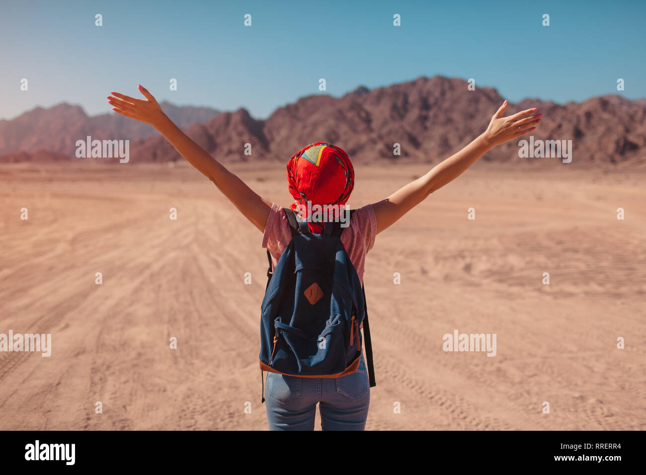 Mujer con mochila turística llevar pañuelo en la cabeza. Viajero feliz  admirando el Sinaí, el desierto y las montañas con manos levantadas.  Vacaciones de verano Fotografía de stock - Alamy