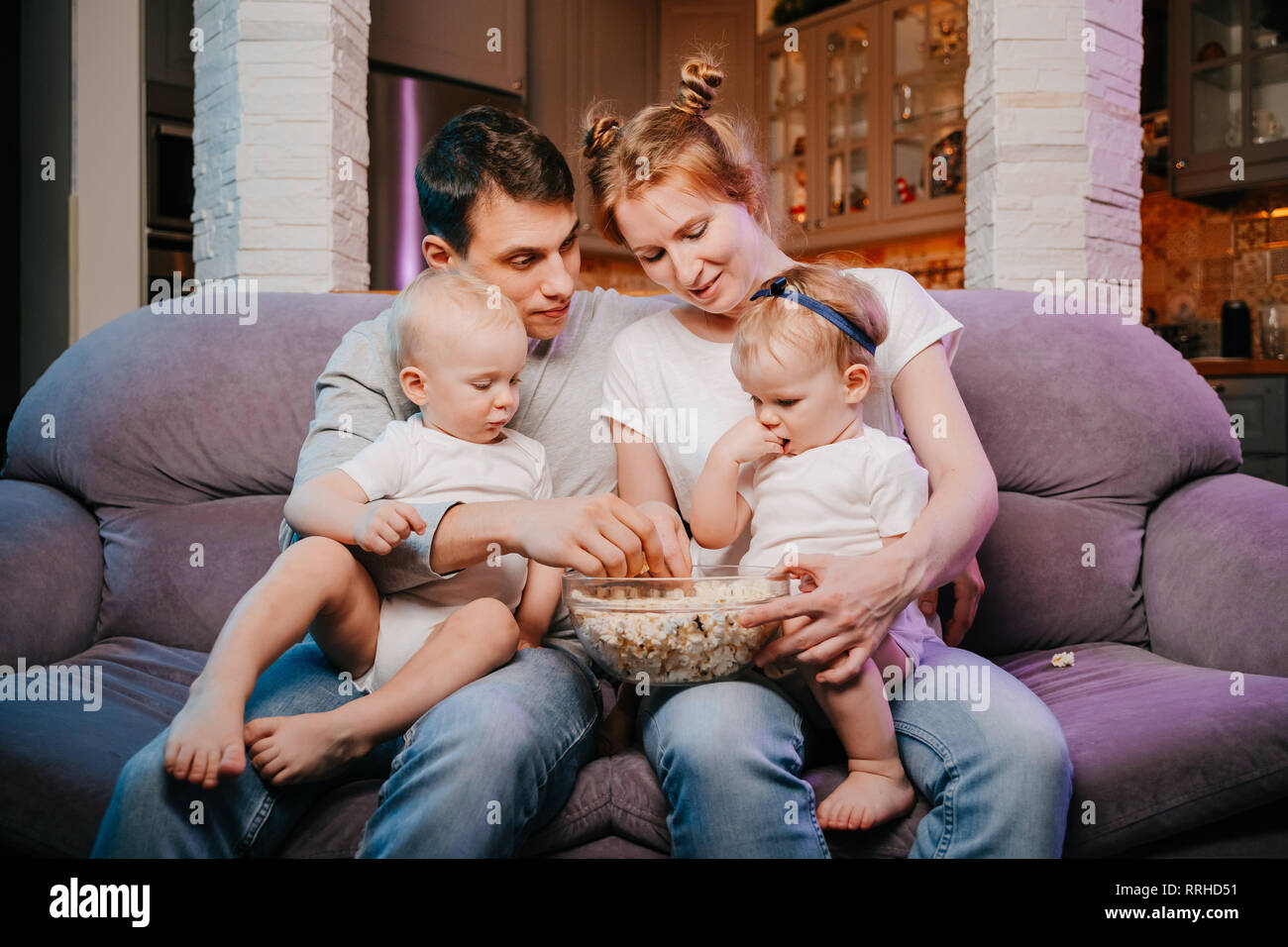 Familia joven con niños comiendo palomitas en el sofá Fotografía de stock -  Alamy