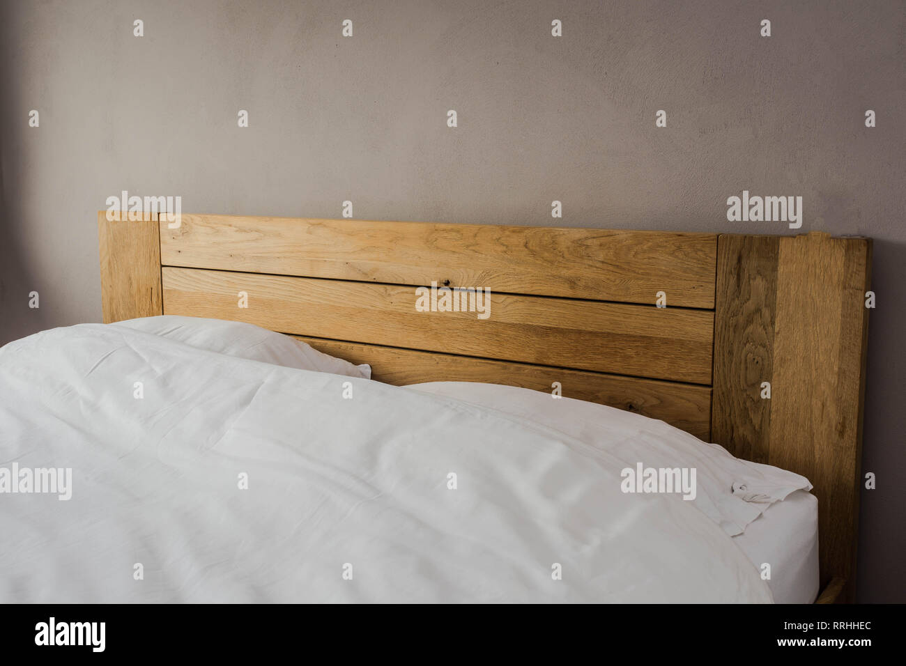 Cama con dos almohadas. sábana blanca sobre la madera, cama de tamaño king  size. el minimalismo en casa Fotografía de stock - Alamy