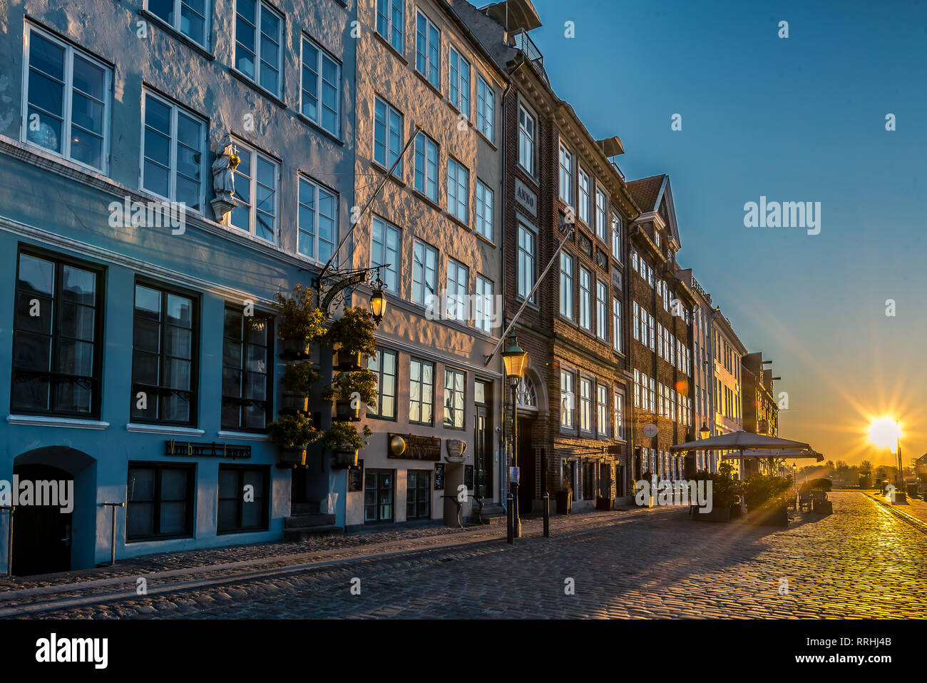 El pavimento y restaurantes cerrados en la primera luz de la mañana brillante en Nyhavn en Copenhague, 16 de febrero de 2019 Foto de stock