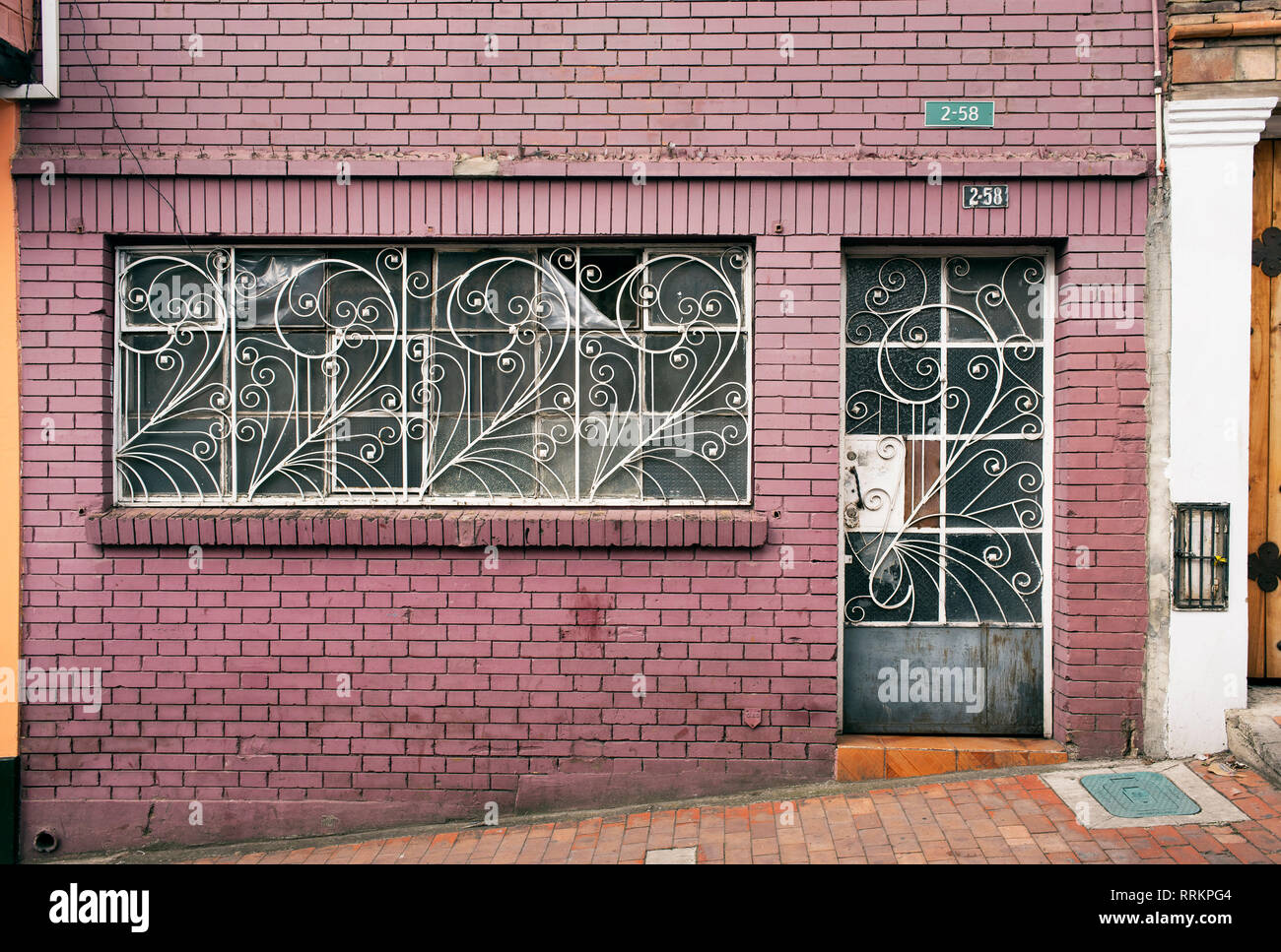 Colorida fachada de edificio residencial con un estilo retro de barras de metal para puertas y ventanas. La Candelaria, Bogotá, Colombia. Sep 2018 Foto de stock