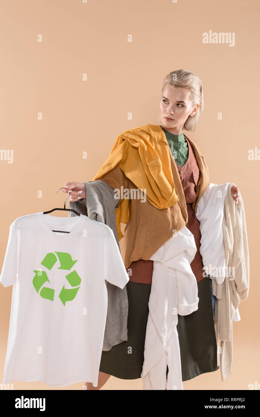 Mujer joven ropa con signo de reciclaje en Hanger aislado en beige, concepto de ahorro ambiental Fotografía de stock -