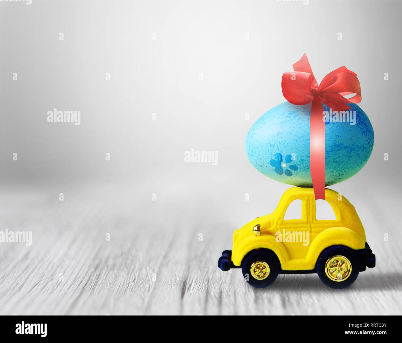 Huevo de pascua y coche de juguete sobre fondo gris, feliz día de Pascua concepto. Foto de stock