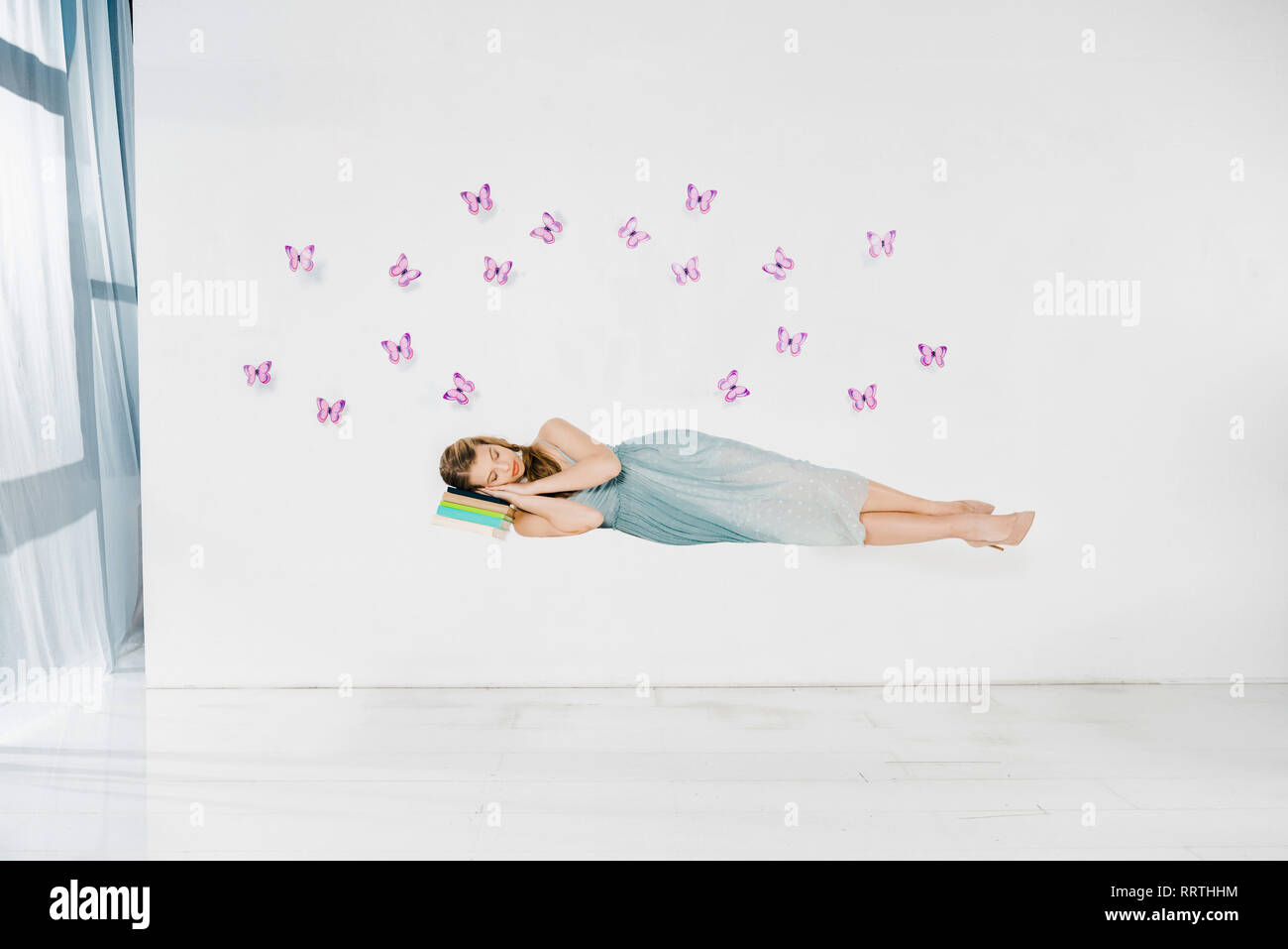 Chica en vestido azul durmiendo en libro en el aire sobre fondo blanco con  morado mariposas Fotografía de stock - Alamy