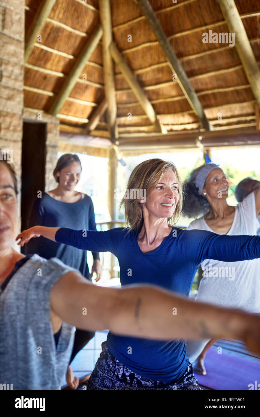 Seguros de mujer practicando guerrero 2 plantean en cabaña durante yoga retreat Foto de stock
