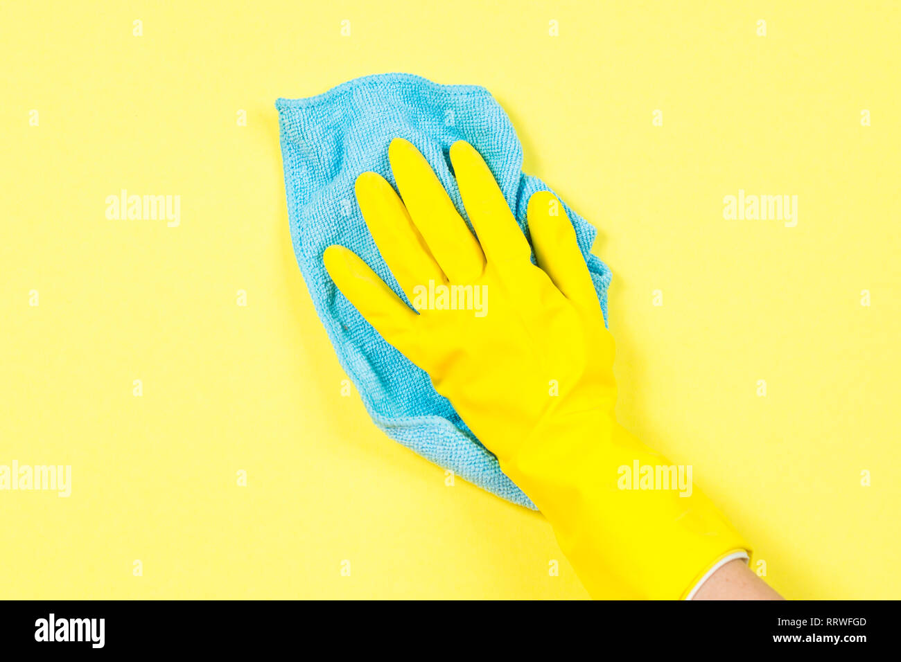 Mano en amarillo y un trapo de limpieza de microfibra guantes de fondo amarillo. Foto de stock
