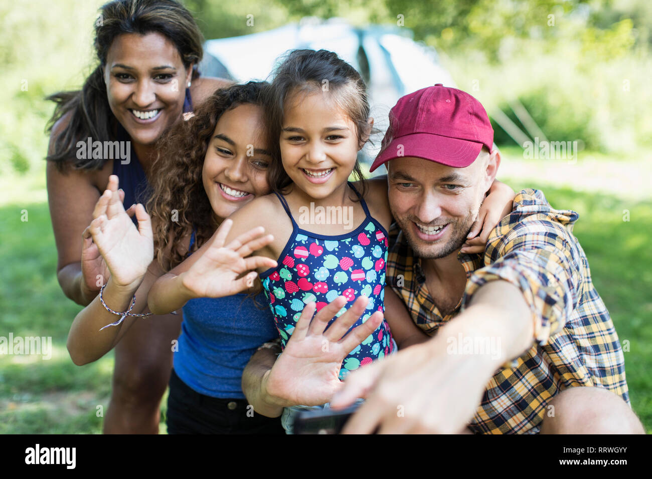 Familia Feliz ondeando, teniendo selfie con cámara teléfono en camping Foto de stock
