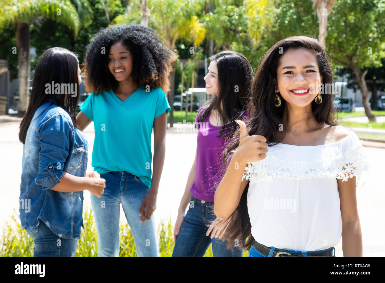 Mujer Asiática mostrando el pulgar con un grupo de amigas al aire libre en el verano en la ciudad Foto de stock