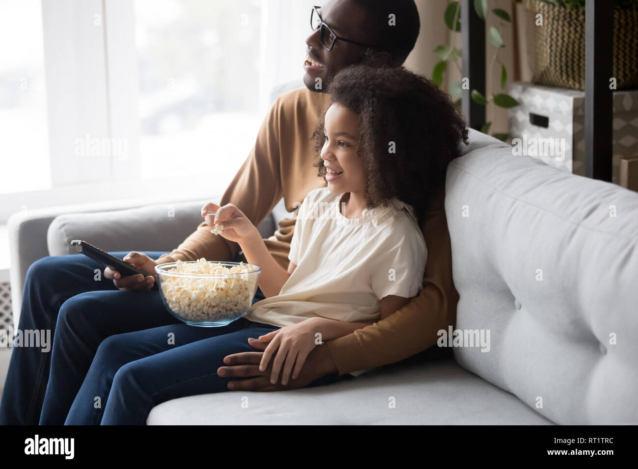 Feliz familia africana papá con hijo hija viendo la televisión juntos Foto de stock