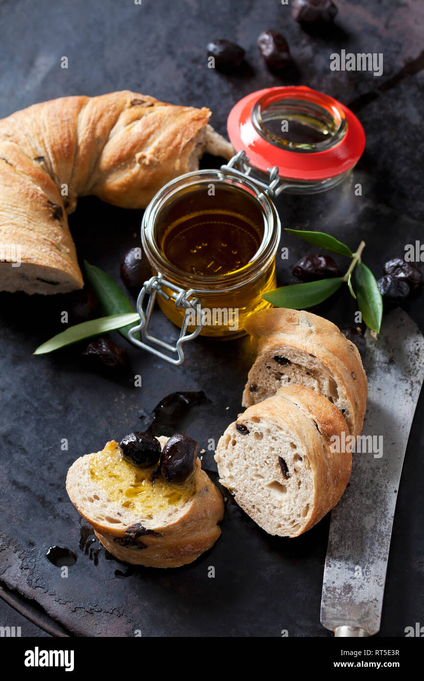 Anillo pan con aceitunas negras, el vaso de aceite de oliva y aceitunas negras Foto de stock