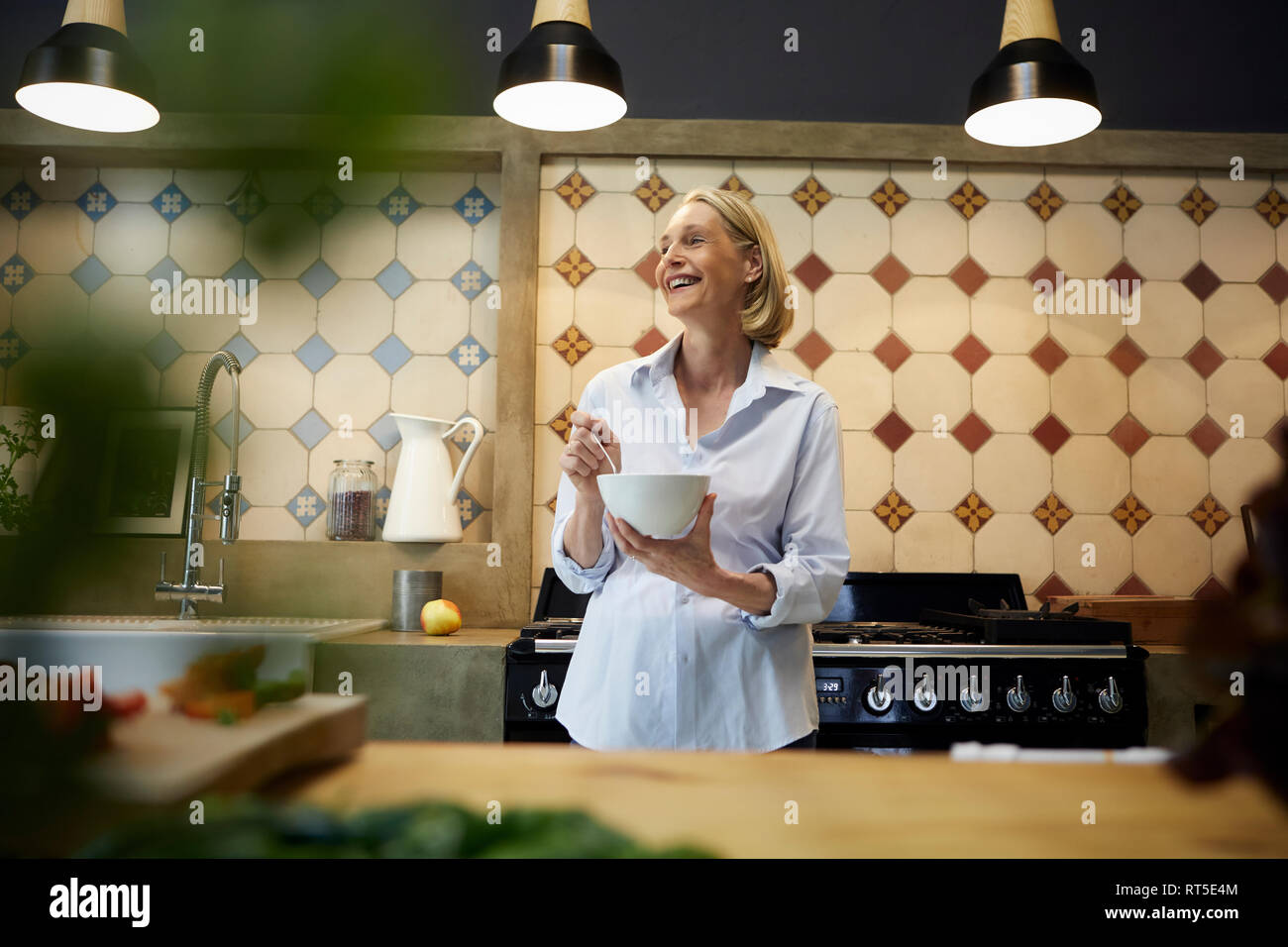 Mujer madura feliz celebración bowl en la cocina Foto de stock