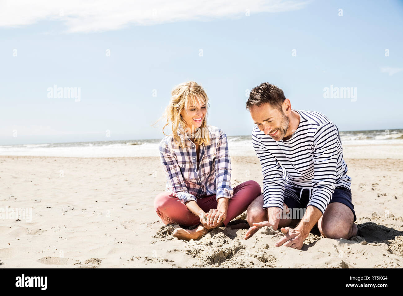 Feliz pareja sentada en la playa Foto de stock