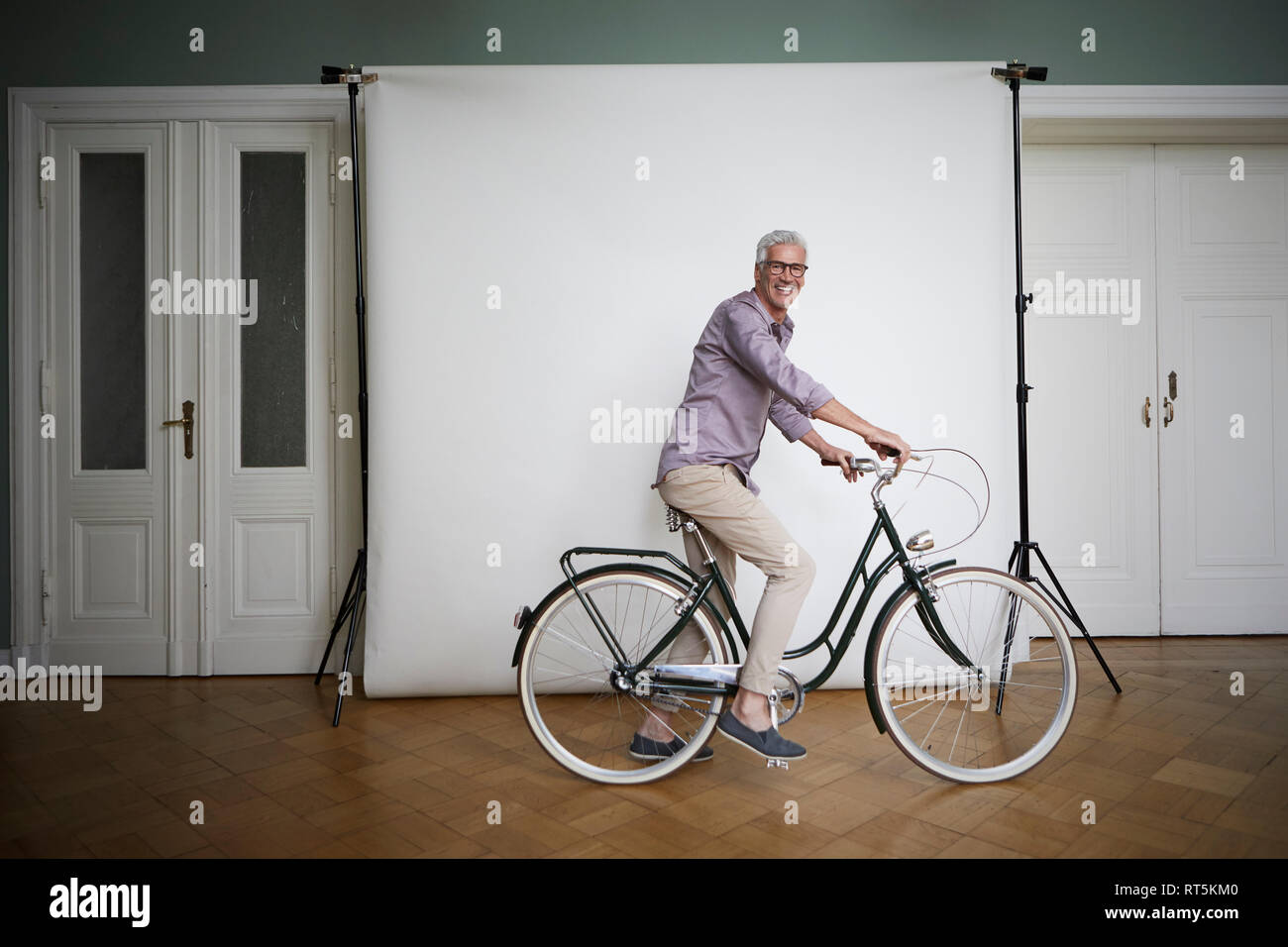 Portait de hombre maduro posando en bicicleta en la pantalla de proyección. Foto de stock