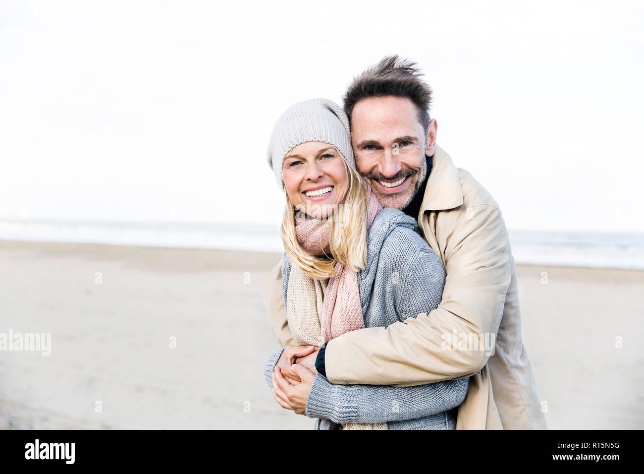 Retrato de pareja feliz abrazando en la playa Foto de stock