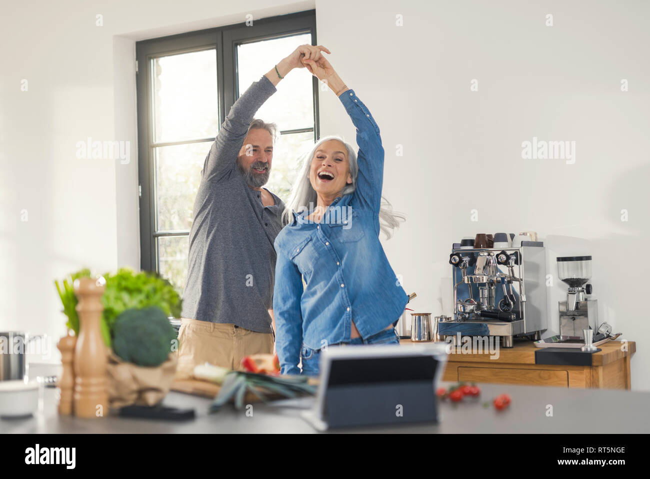 Senior joven pareja bailando en la cocina Foto de stock