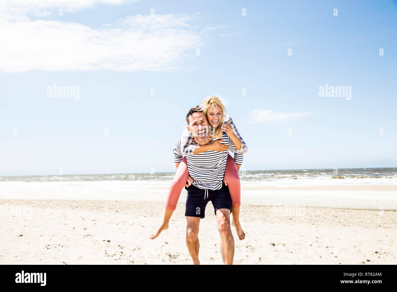 Feliz pareja juguetona en la playa Foto de stock