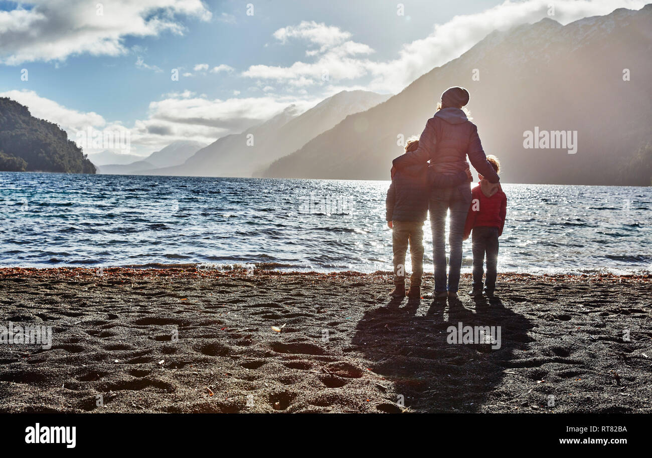 Argentina, Patagonia, el Lago Nahuel Huapi, una mujer con dos hijos de pie a la orilla del mar, con vistas al lago Foto de stock