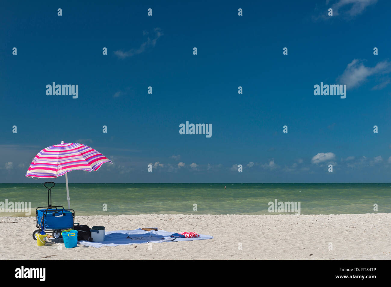 Estados Unidos de América, Florida, Fort Myers, Sanibel Island, Sanibel, sombrilla y equipo de playa en frente del mar, con el cielo azul Foto de stock