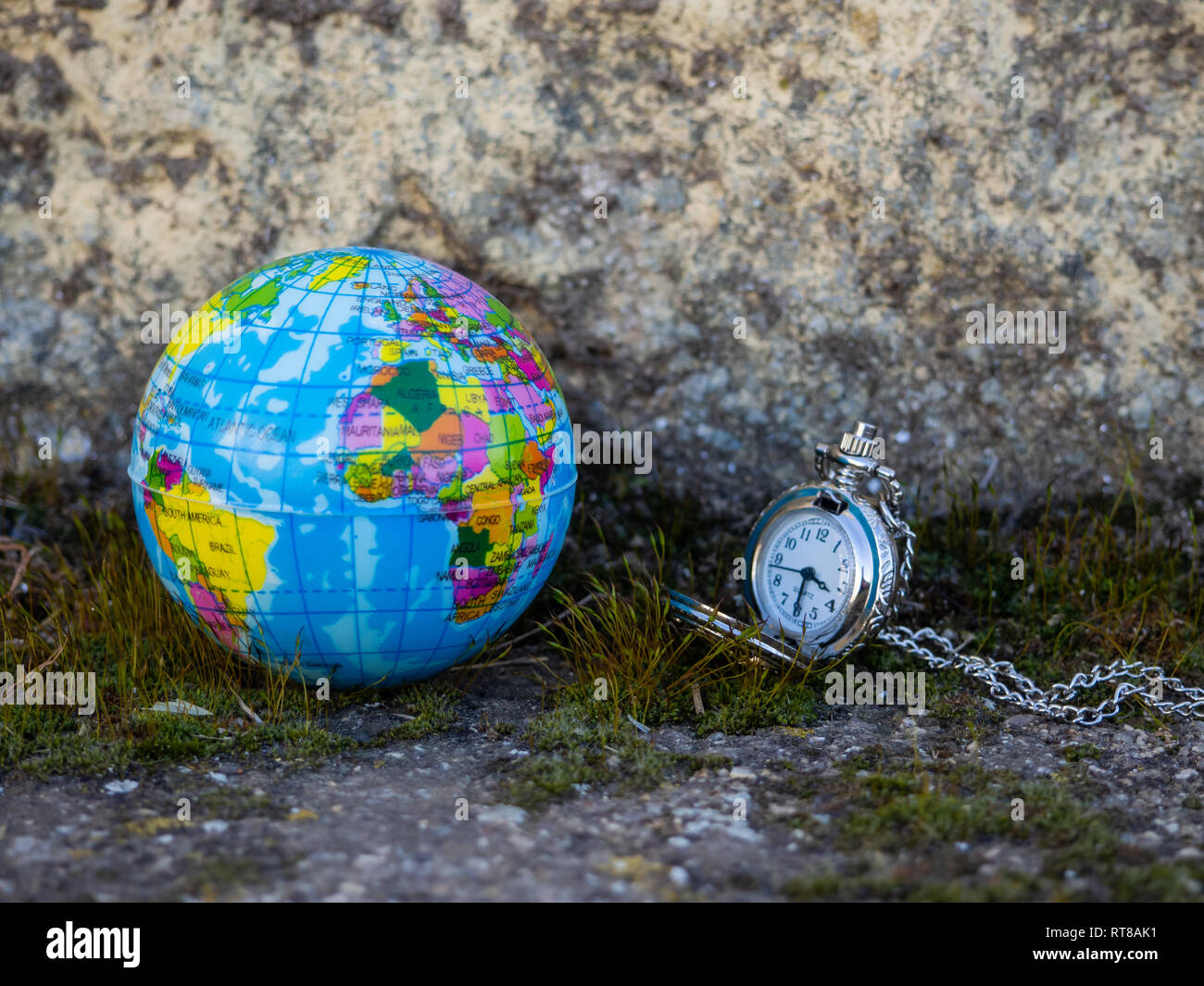 Un globo terrestre cerca de un reloj analógico. Concepto de ecología Foto de stock