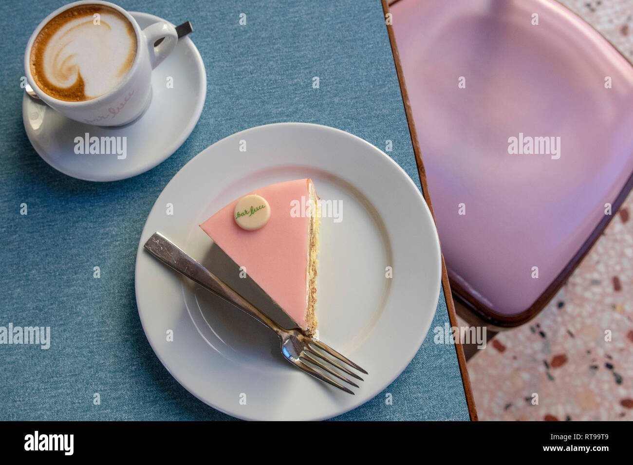 Cappuccino, Torta rosa pastel y mobiliario en el Bar Luce, Wes Anderson-bar y cafetería inspirada en la Fondazione Prada distrito de Milan, Italia. Foto de stock