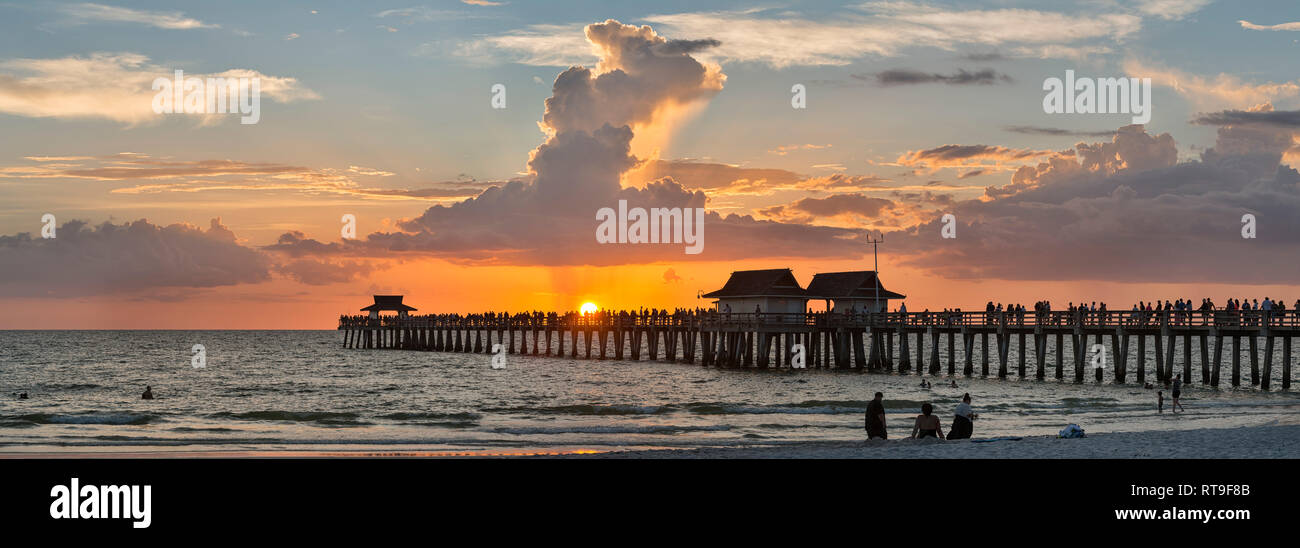Estados Unidos de América, Florida, Nápoles, siluetas de Nápoles Pier y turistas con una enorme nube de lluvia encima durante la puesta de sol Foto de stock