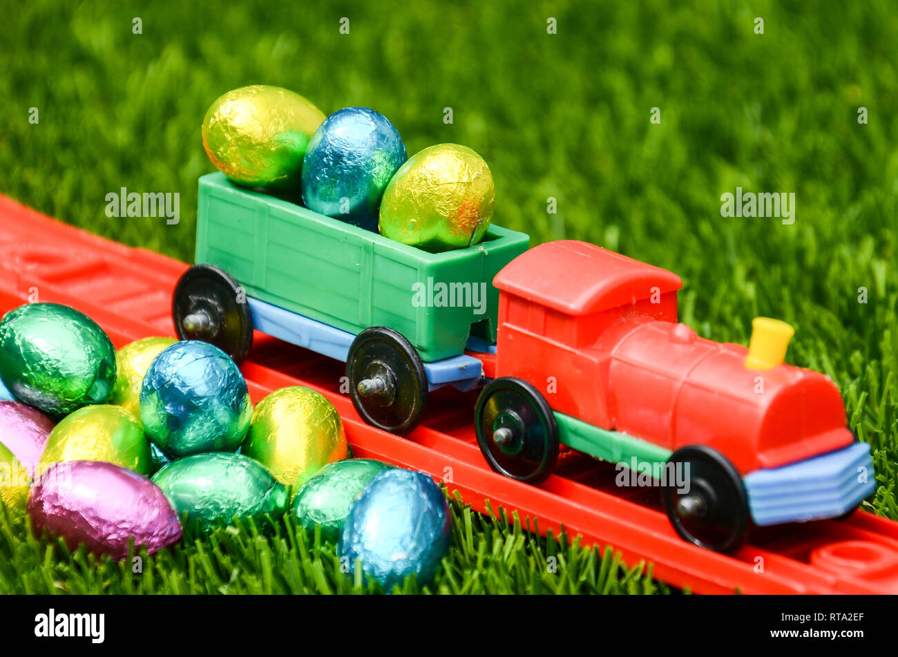 Tren de juguete divertido de colores brillantes con una carga de huevos de  Pascua y de la pila de huevos de Pascua sobre el césped. Concepto de  Pascua, vacaciones, jugar y la