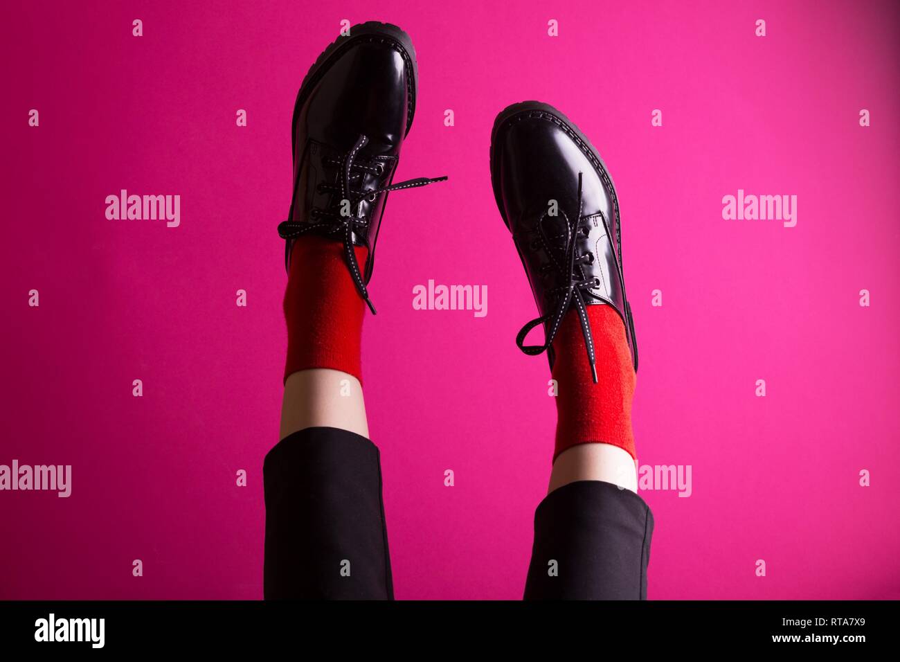 Piernas femeninas en calcetines rojos y elegantes zapatos negros sobre un  fondo de color rosa. tendencias de la moda, zapatos de mujer hermosa  Fotografía de stock - Alamy