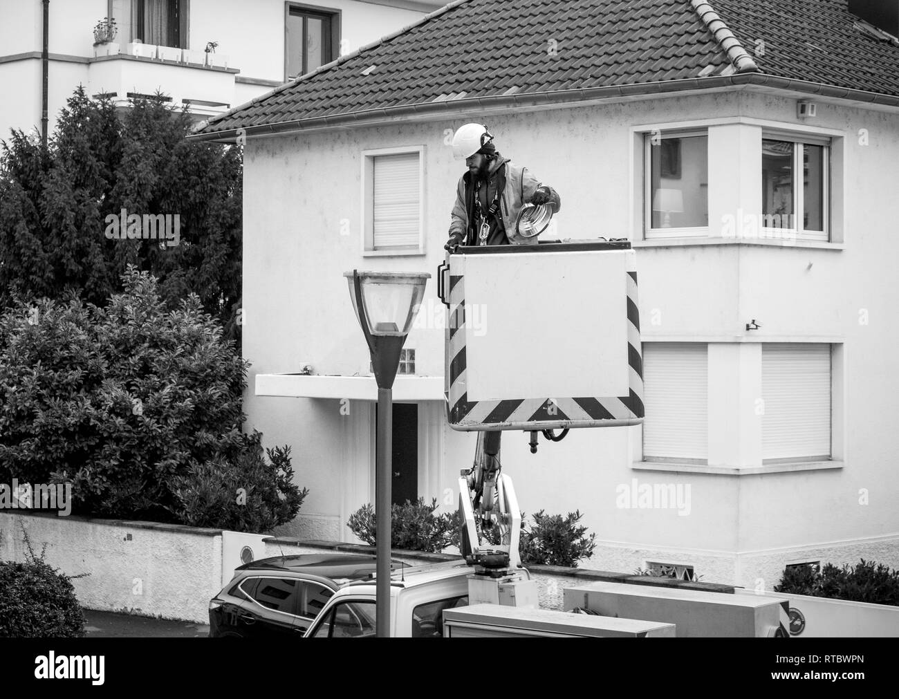 París, Francia - DEC 16, 2017: limpieza trabajador reparar cambiando el tubo luminoso de un mástil ligero en París por la noche, la seguridad y la protección en el barrio Foto de stock