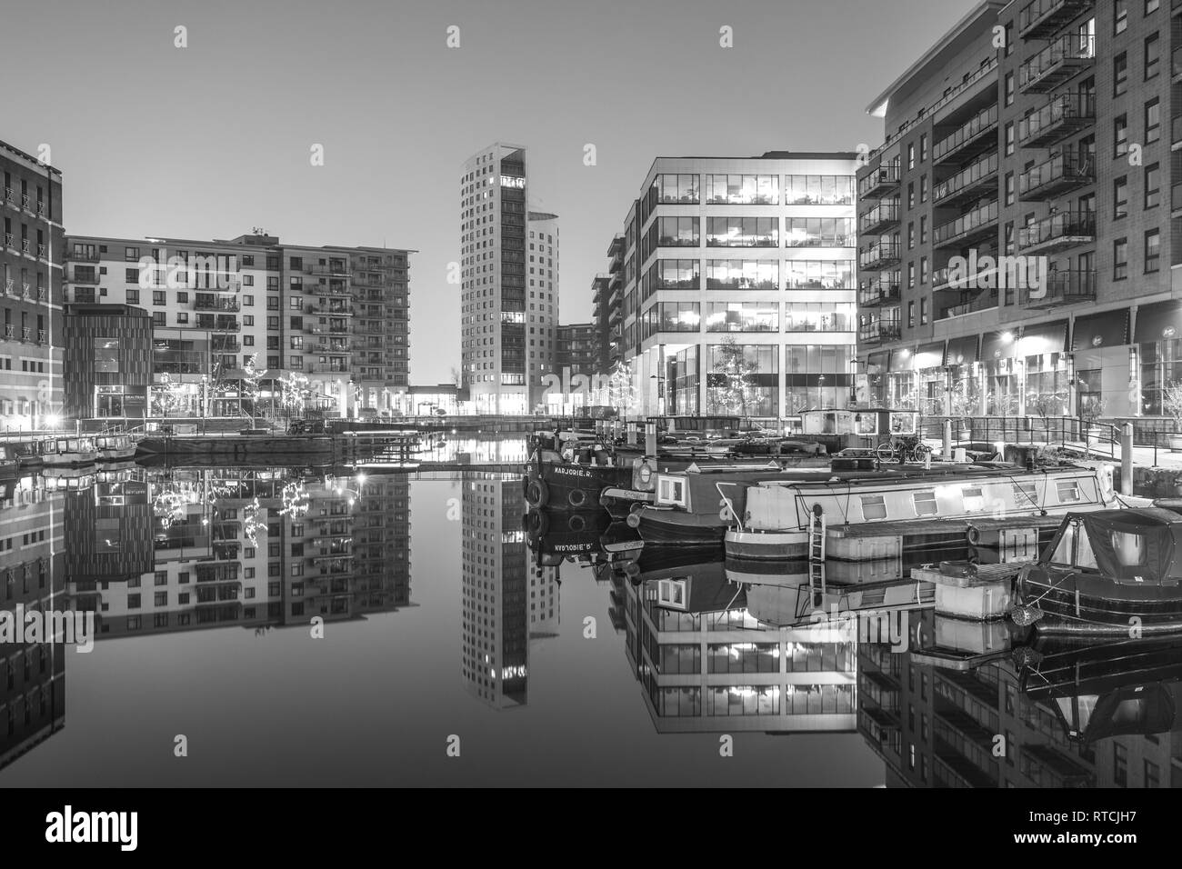 Reflexiones de amarrados narrowboats y apartamentos en Leeds Dock Foto de stock