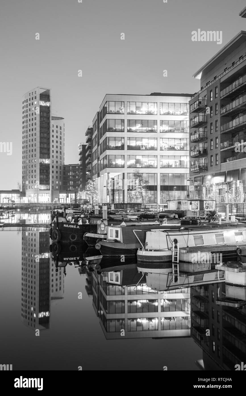 Reflexiones de amarrados narrowboats y apartamentos en Leeds Dock Foto de stock