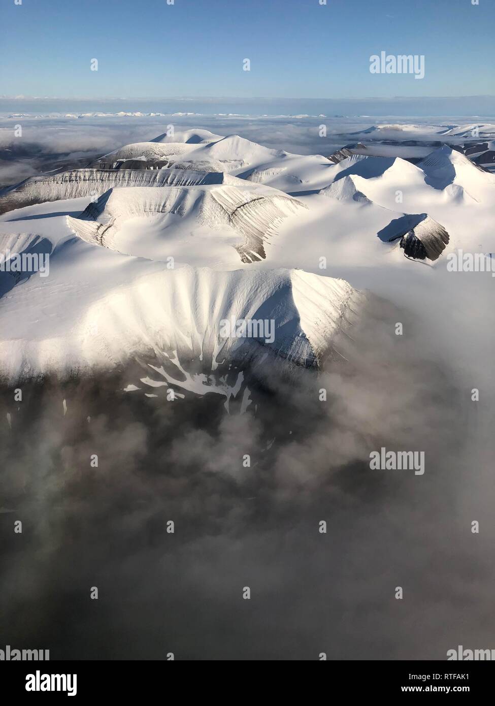 Vista aérea, el pico de la montaña con nieve por encima de la cubierta de nubes, Spitsbergen, Svalbard, Noruega Foto de stock