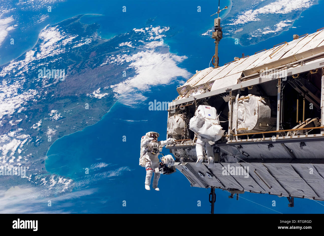 Astronautas en una caminata espacial y la Estación Espacial Internacional Con una vista de la Tierra Foto de stock